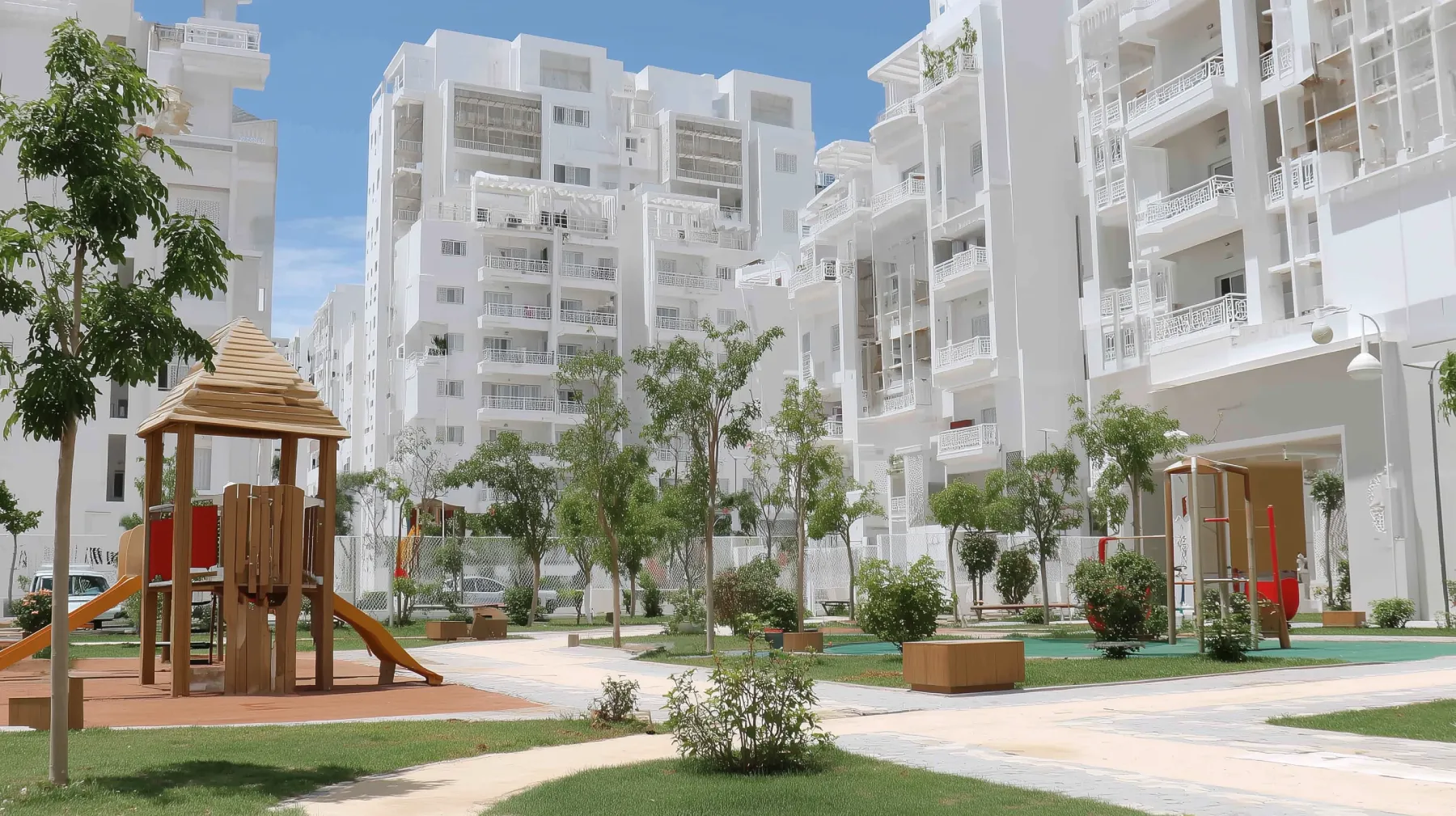 Residential complex in Tangier with white multi-storey buildings, children's playground, and landscaped communal gardens