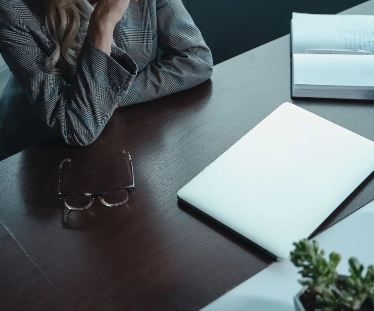 Executive assistant in Rabat seated at a desk with a laptop, notebook and glasses in a modern office