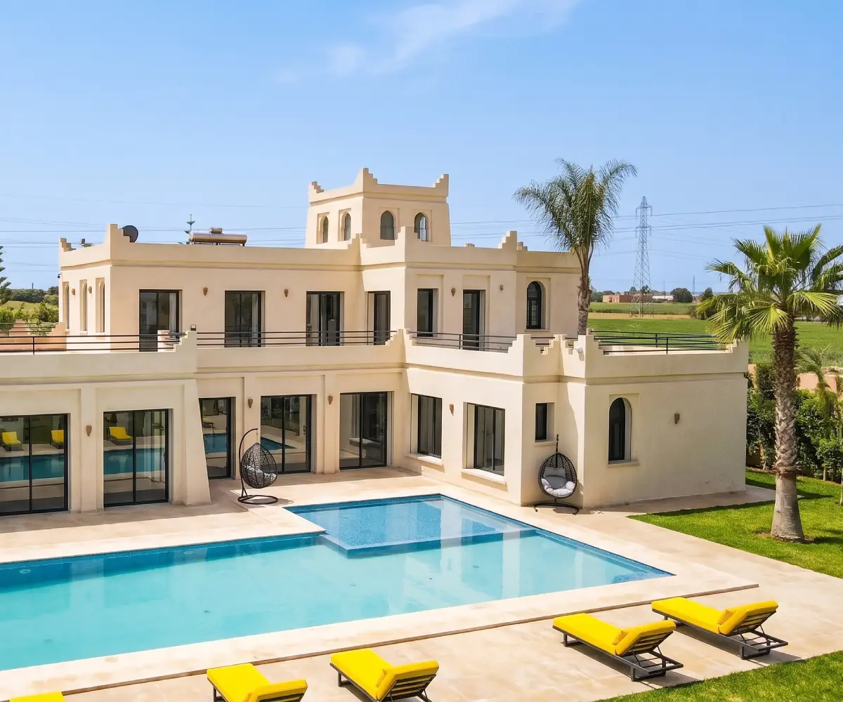 Moroccan-style villa near Casablanca with a crenellated tower, arched windows and yellow loungers by the pool