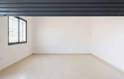 Interior of a garage for rent in Agadir with raised roller shutter, barred window and pale tiled flooring