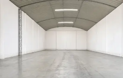 Warehouse for rent in Bouskoura with a curved metal roof, twin ceiling lights and a steel lattice support column