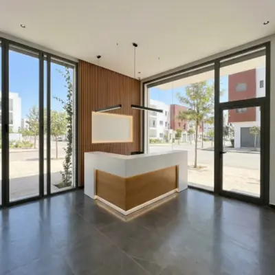Reception area in a Meknes commercial unit with white and oak L-shaped desk, slatted wood wall and full-height glazing